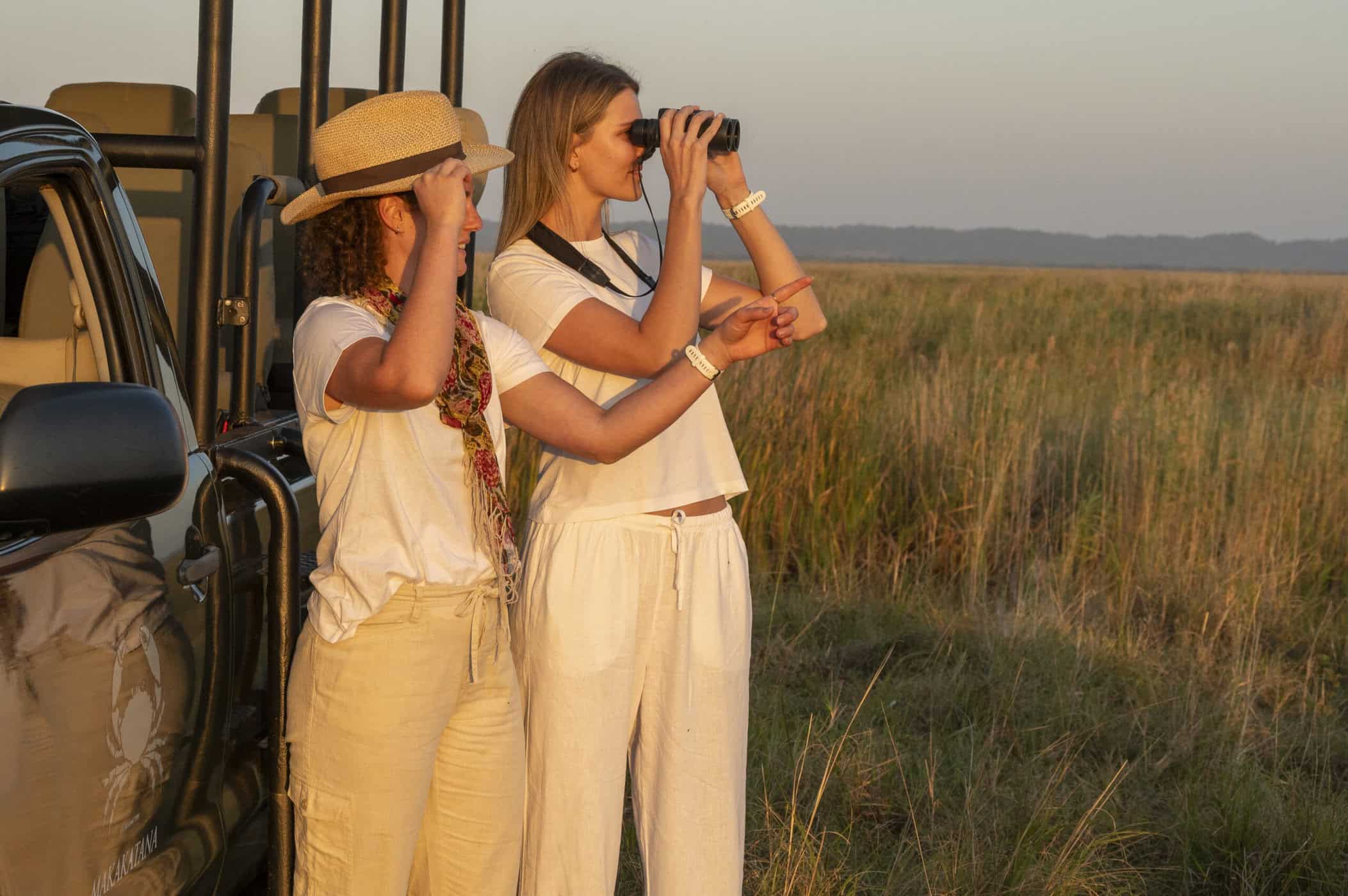 ladies looking through binoculars in front of game vehicle