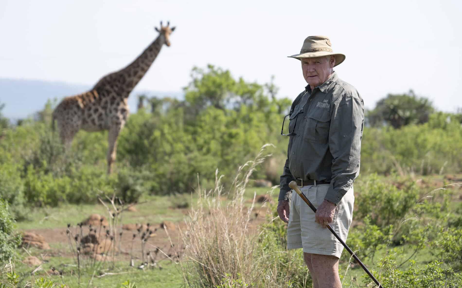 guide standing in front of giraffe