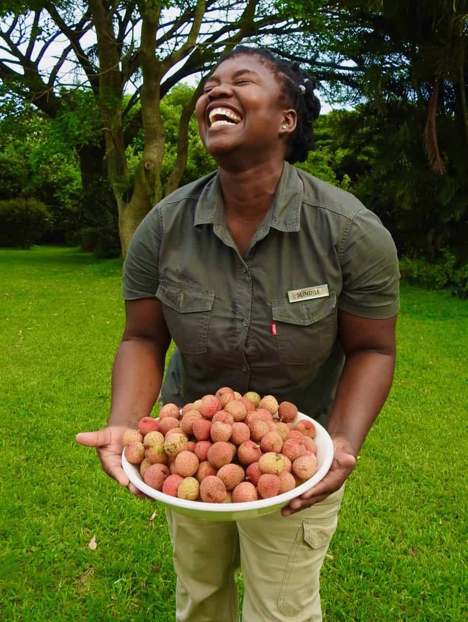 staff member laughing with tray of litchis